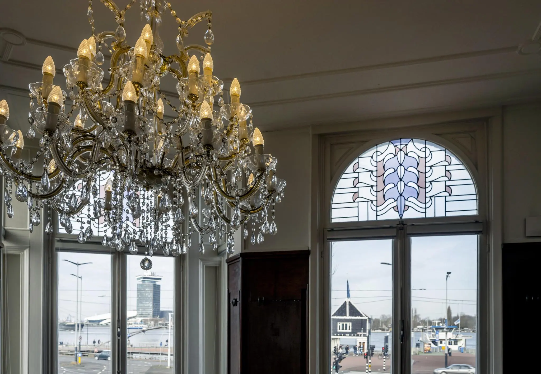 Kristallen kroonluchter in een klassiek interieur met uitzicht op de De Ruijterkade in Amsterdam.